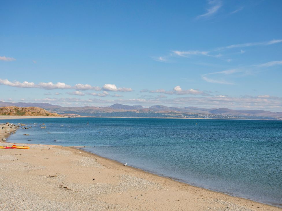 A beach with water and mountains in the background at East meets West Criccieth
