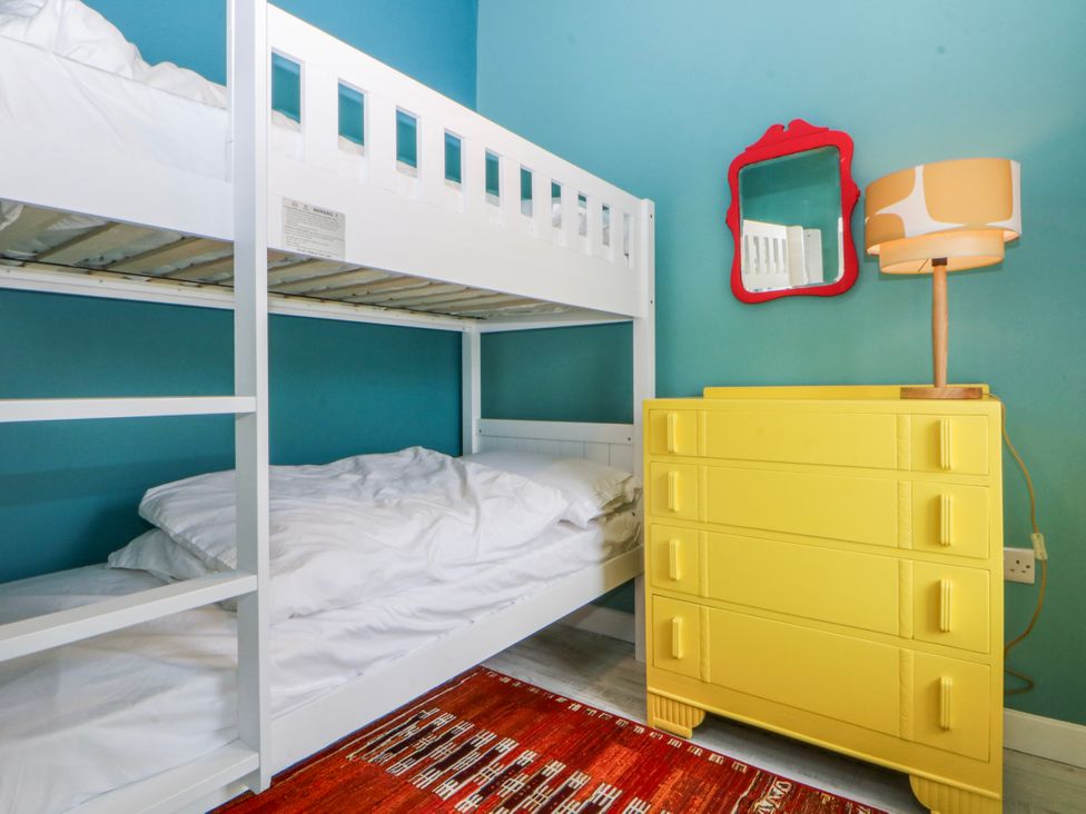 A bedroom with a bunk bed and yellow dresser at East meets West Criccieth