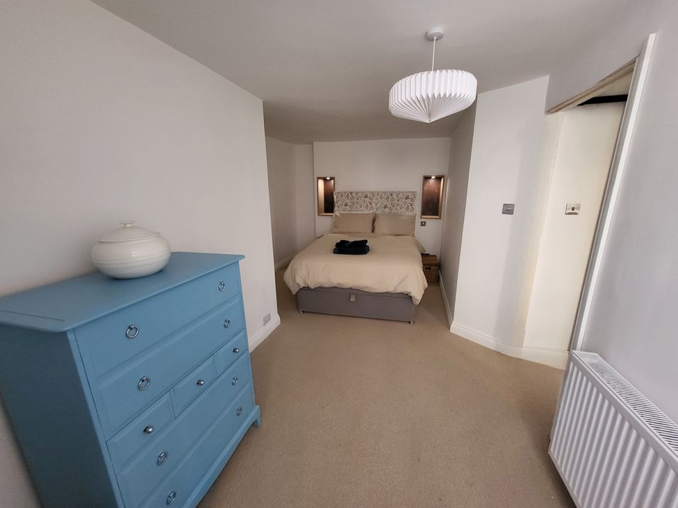 A bedroom with a bed and dresser at Fishermans Locker in West Bay