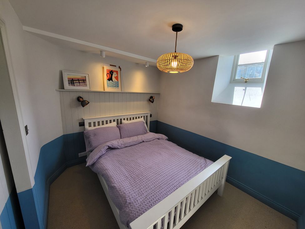 A bedroom with a bed and wall art at Fishermans Locker in West Bay