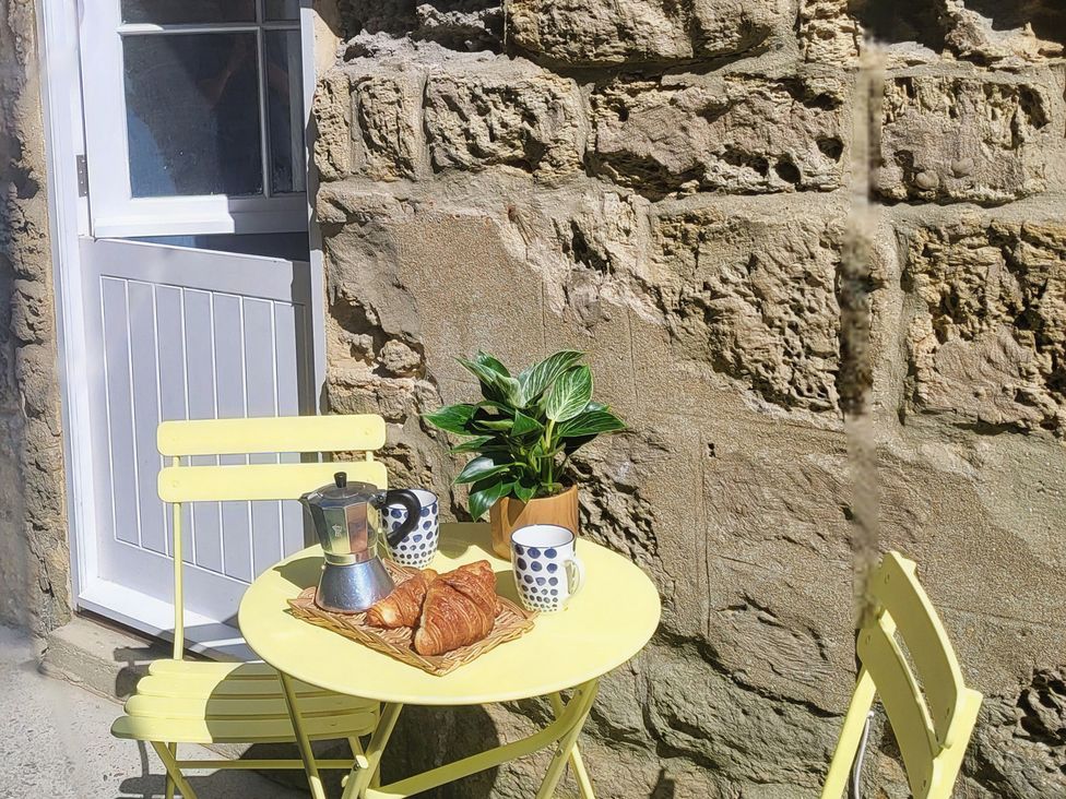 An outdoor seating area with a table and chairs at Fishermans Locker in West Bay