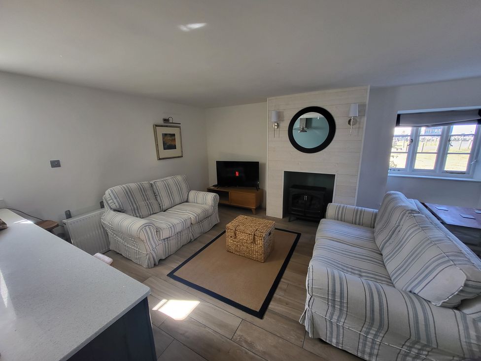 A living room with sofas and a television at Fishermans Locker in West Bay