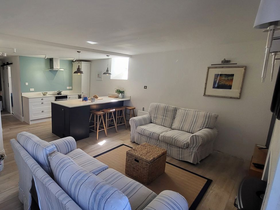 A living room with a sofa and kitchen island at Fishermans Locker in West Bay