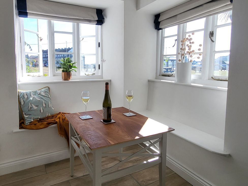 A dining room with a table and wine glasses at Fishermans Locker in West Bay