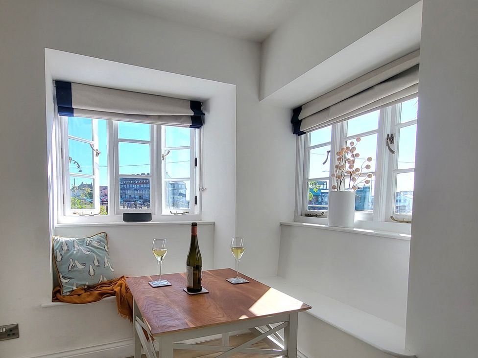 A dining area with a wooden table and wine glasses at Fishermans Locker in West Bay