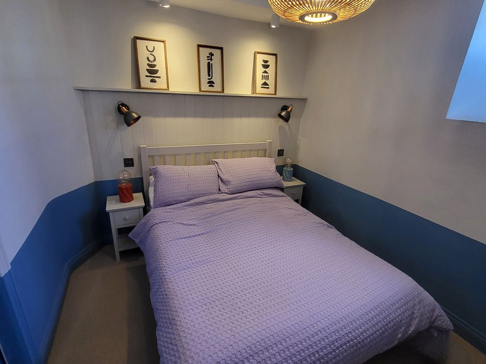A bedroom with a bed and wall art at Fishermans Locker in West Bay