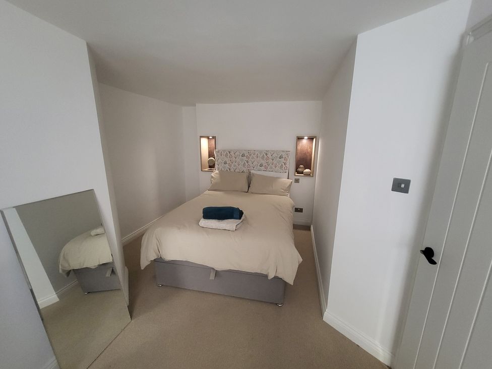 A bedroom with a bed and mirror at Fishermans Locker in West Bay