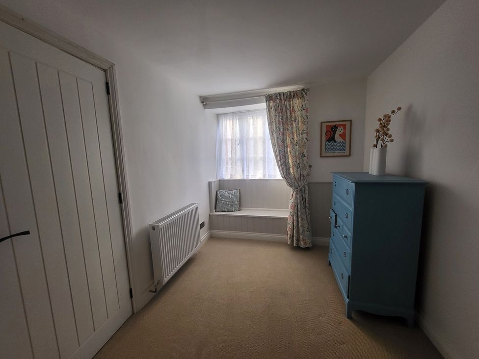 A bedroom with a window and a blue dresser at Fishermans Locker in West Bay