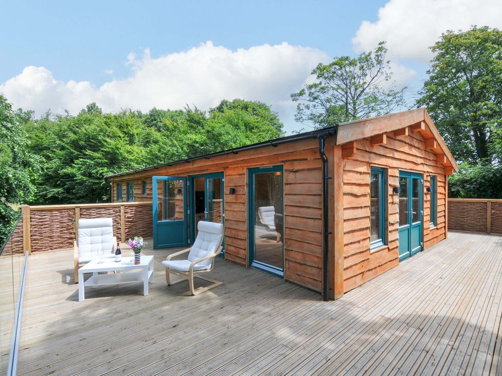 An outdoor patio with chairs and a table at Owl Lodge in Menheniot