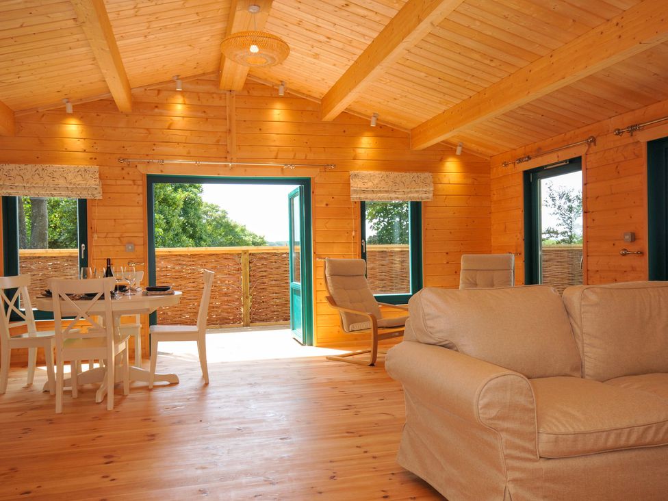 A living room with a wooden table and chairs at Owl Lodge in Menheniot