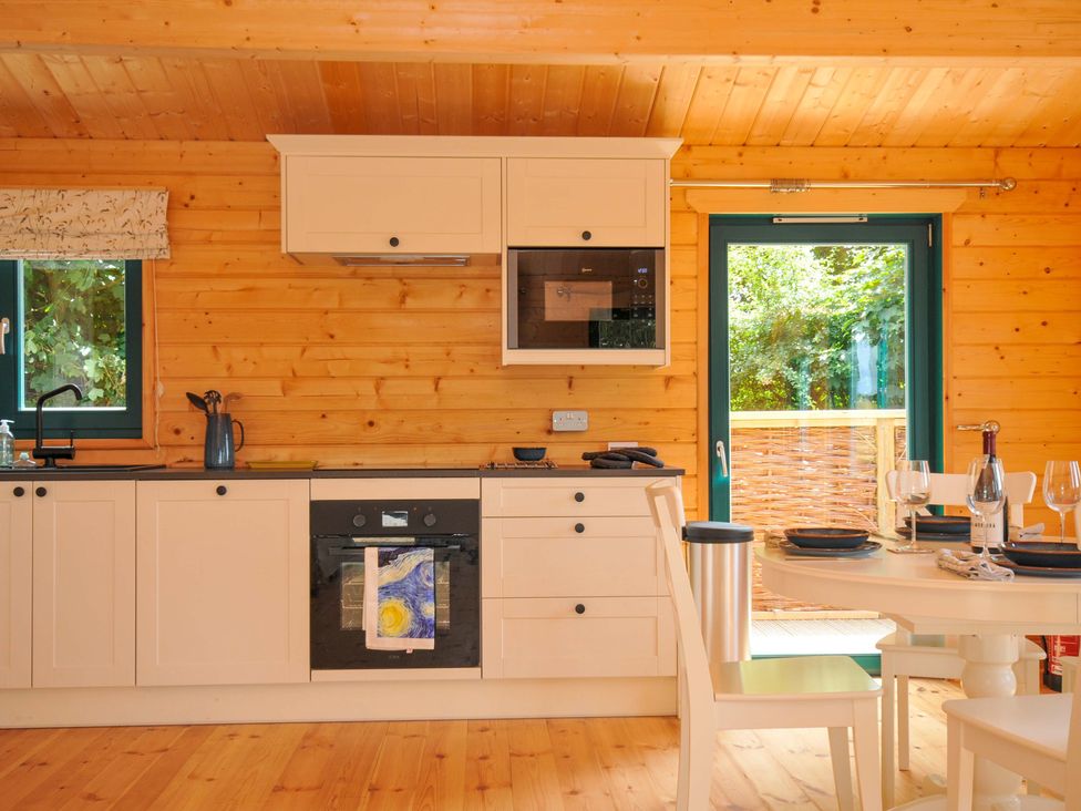 A kitchen with appliances and dining area at Owl Lodge Menheniot