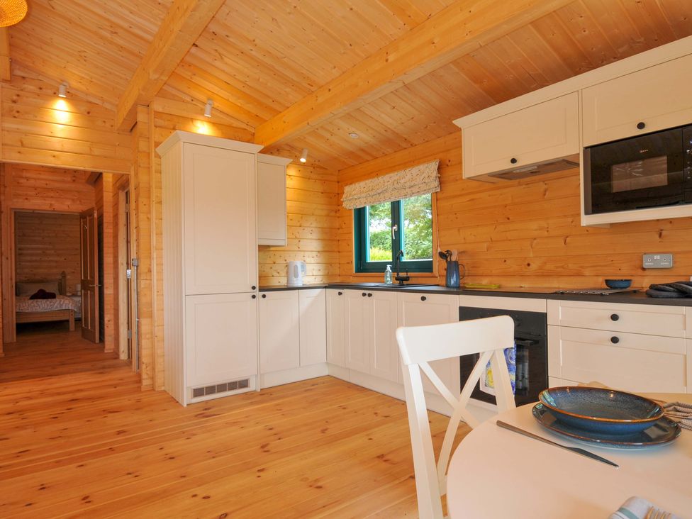 A kitchen with wooden walls and cabinets at Owl Lodge in Menheniot