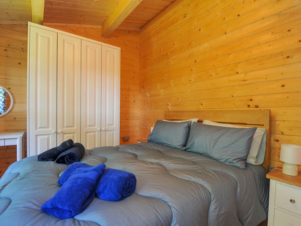 A bedroom with a bed and wardrobe at Owl Lodge in Menheniot