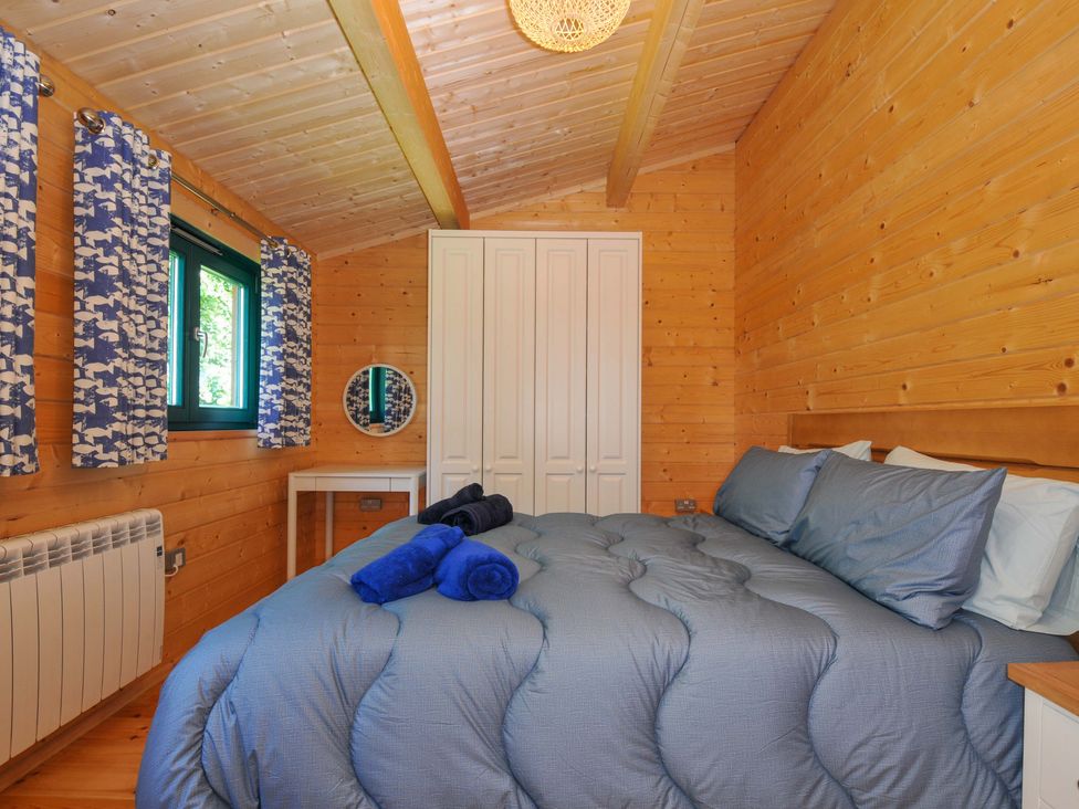 A bedroom with a bed and blue decor at Owl Lodge in Menheniot