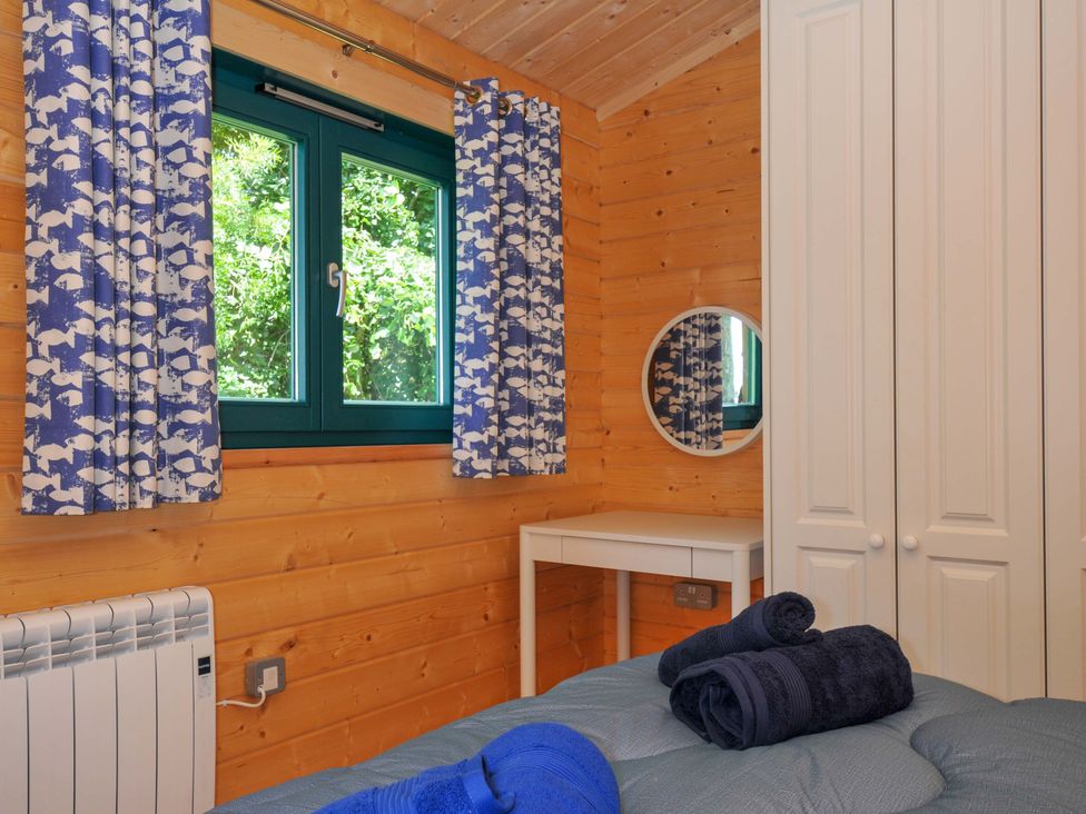 A bedroom with a bed and a wardrobe at Owl Lodge in Menheniot