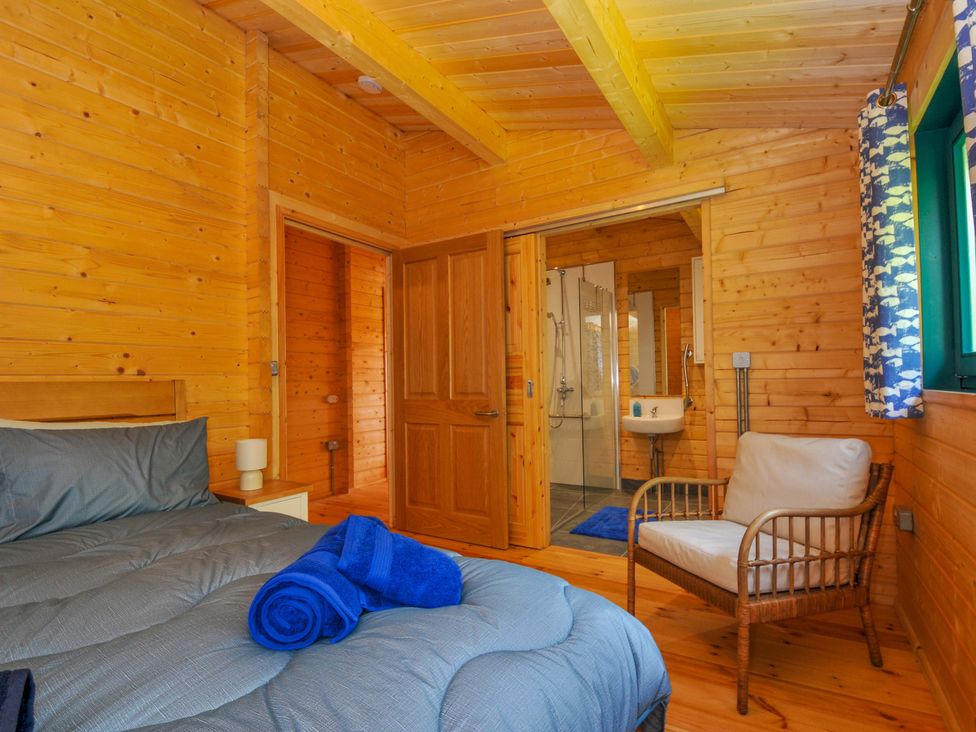 A bedroom with a bed and shower in a cabin at Owl Lodge in Menheniot
