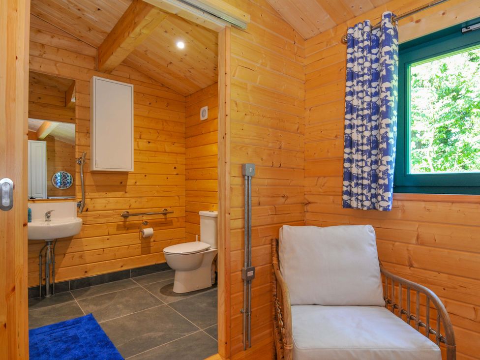 A bathroom with a toilet, sink, and chair at Owl Lodge in Menheniot