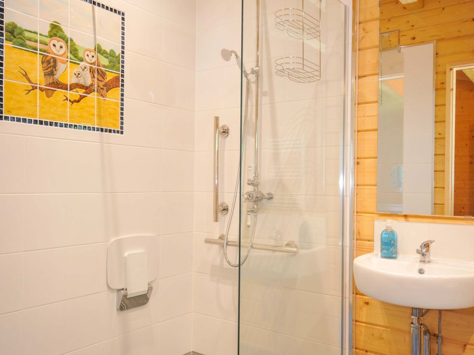 A bathroom with a shower, sink, and mirror at Owl Lodge Menheniot