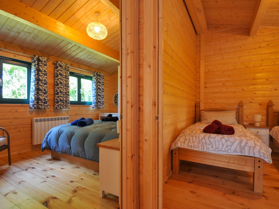 A bedroom with beds and windows at Owl Lodge in Menheniot