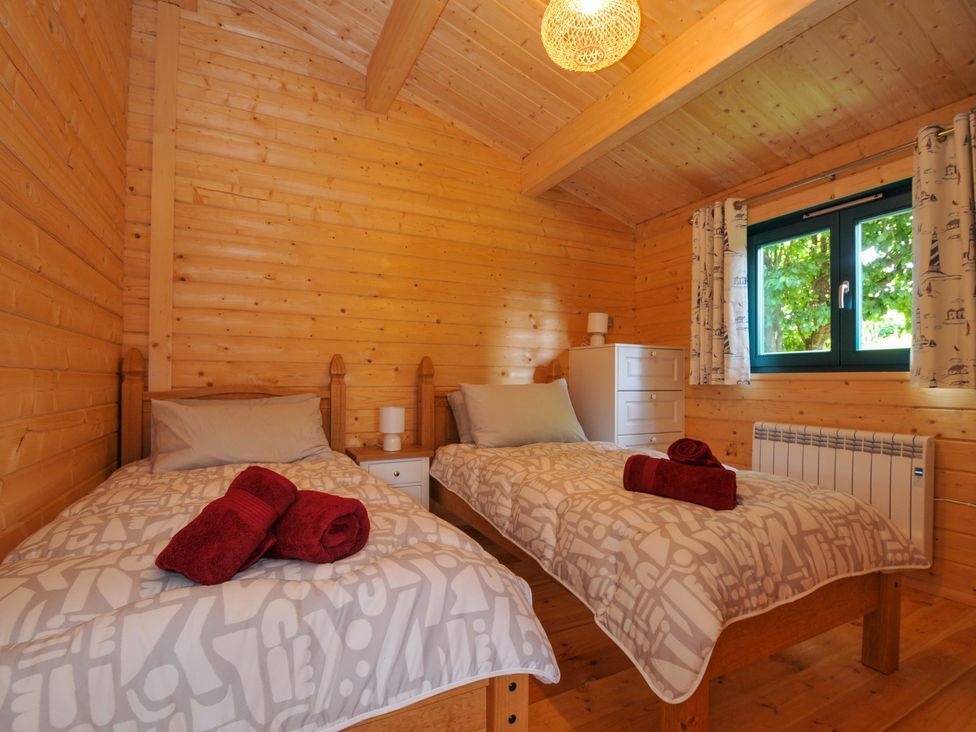 A bedroom with two beds and a chest of drawers at Owl Lodge in Menheniot