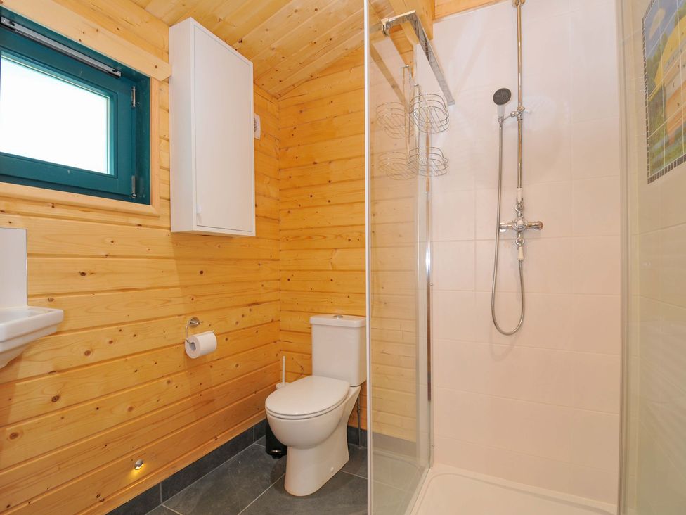 A bathroom with a shower, toilet, and sink at Owl Lodge in Menheniot
