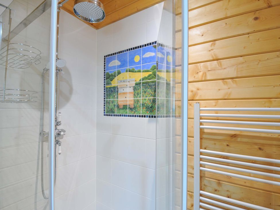 A shower with a mosaic tile in a wooden bathroom at Owl Lodge Menheniot