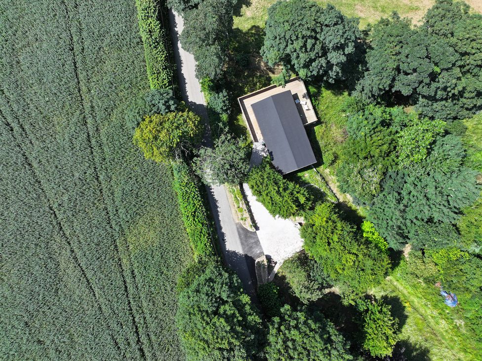 An aerial view of a house surrounded by trees and a road at Owl Lodge in Menheniot