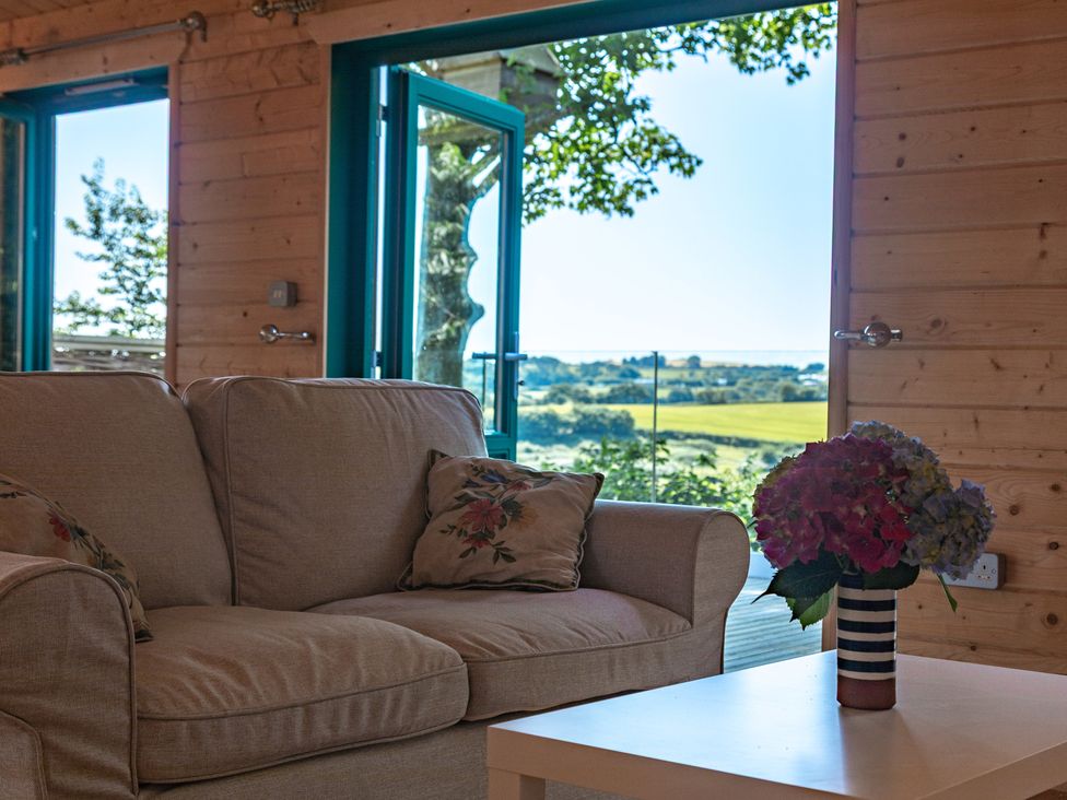 A living room with a sofa and a table at Owl Lodge in Menheniot