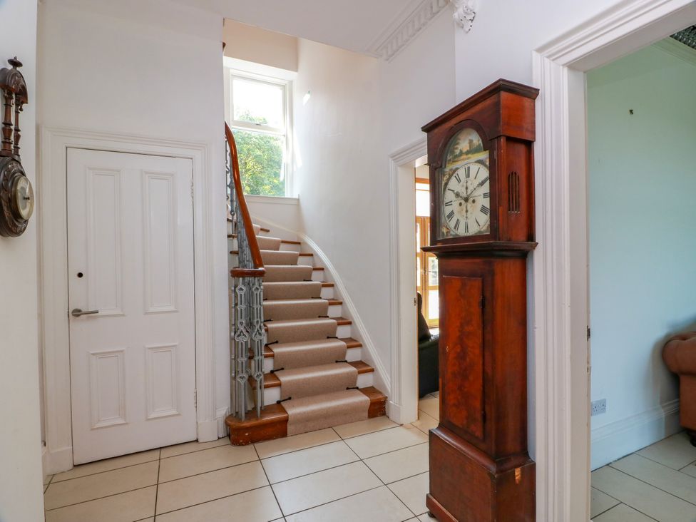 A hallway with a staircase and a clock at Altafearn in Tighnabruaich
