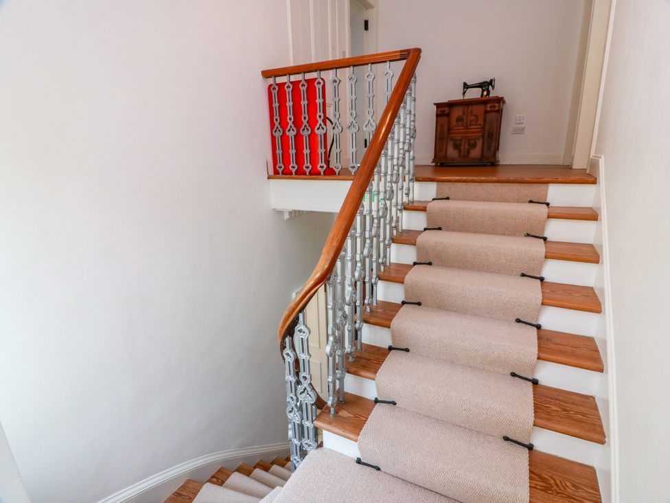 A staircase with a wooden handrail and small table at Altafearn Tighnabruaich