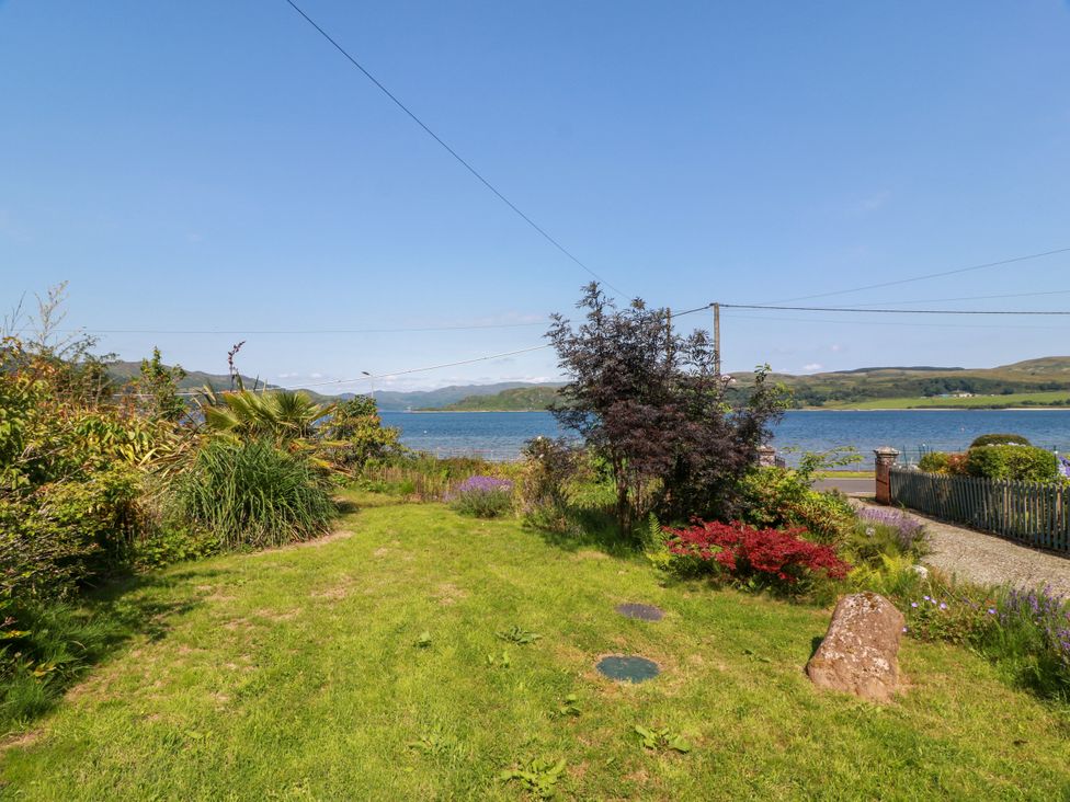 A garden with plants and a view of the water at Altafearn in Tighnabruaich