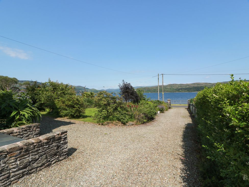 A gravel path leading to a lake with hedges and garden at Altafearn Tighnabruaich