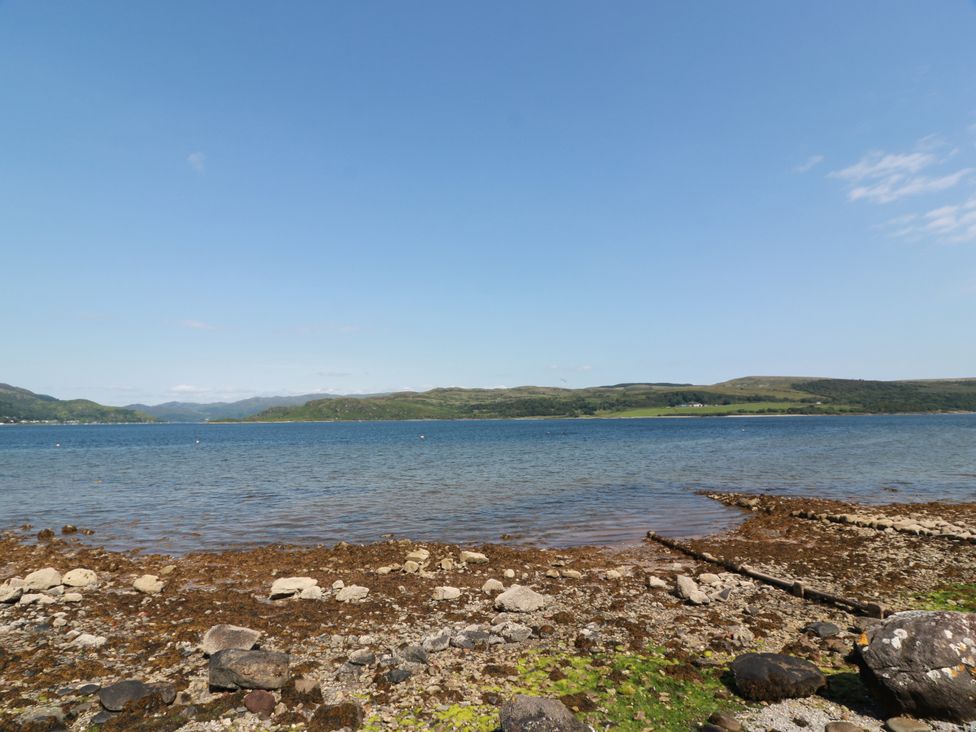 A shoreline with rocks and seaweed along the water at Altafearn in Tighnabruaich