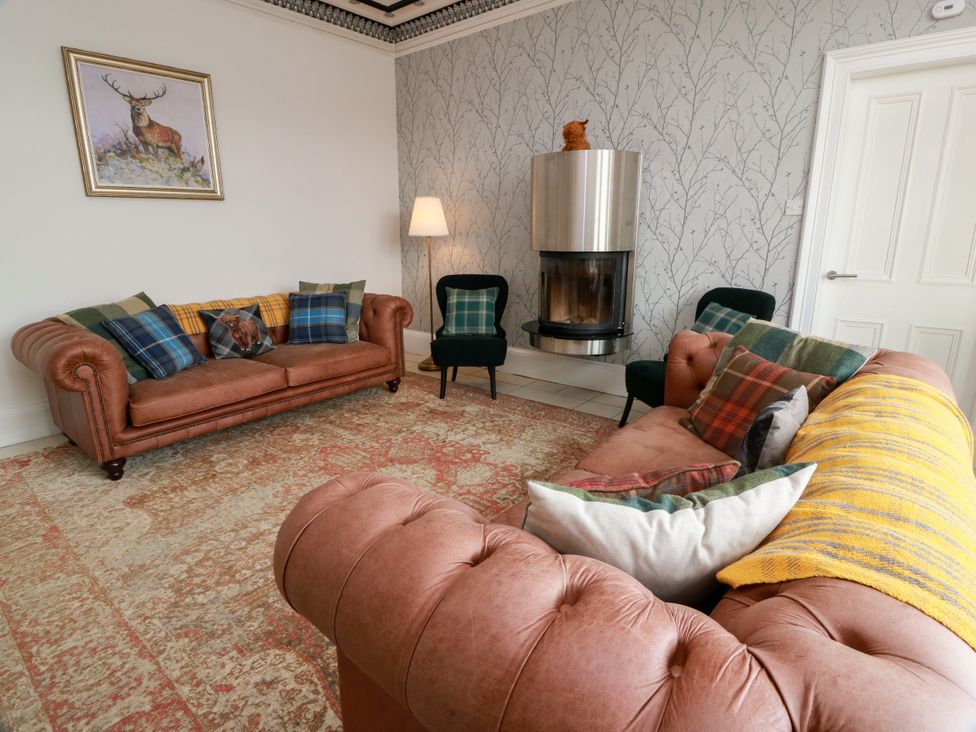 A living room with leather sofas and a fireplace at Altafearn in Kames