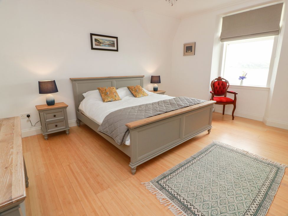 A bedroom with a bed, nightstand, lamp and chair at Altafearn in Kames