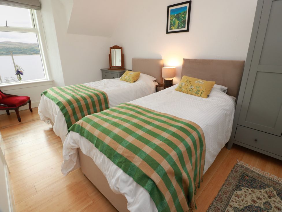 A bedroom with two beds and a window facing water at Altafearn in Kames