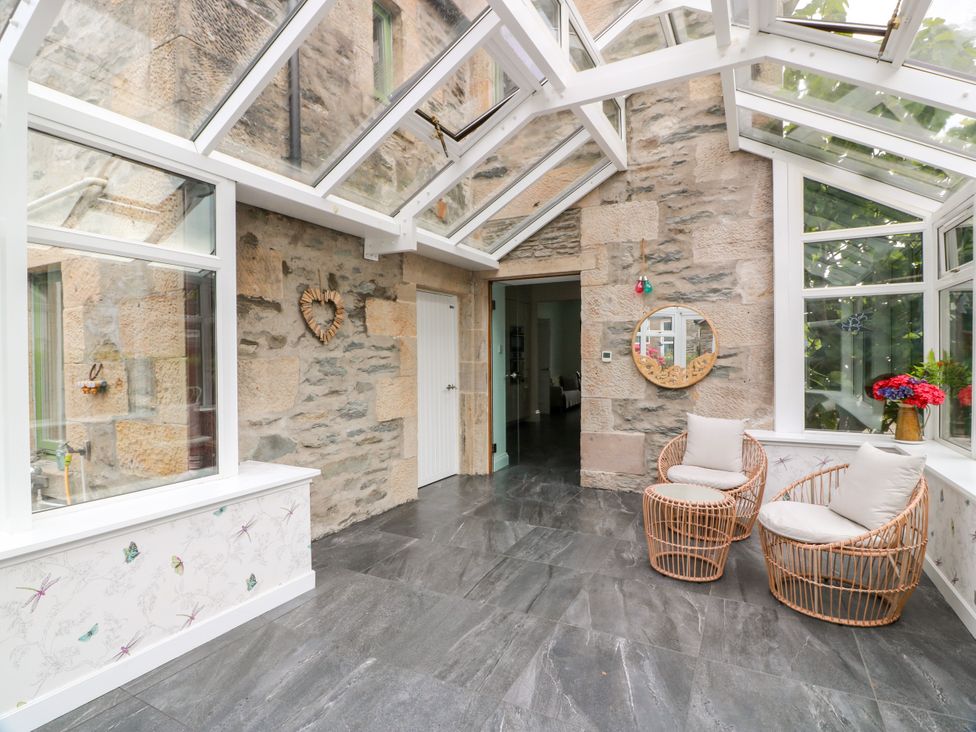 A conservatory with glass roof and wicker chairs at Altafearn in Kames