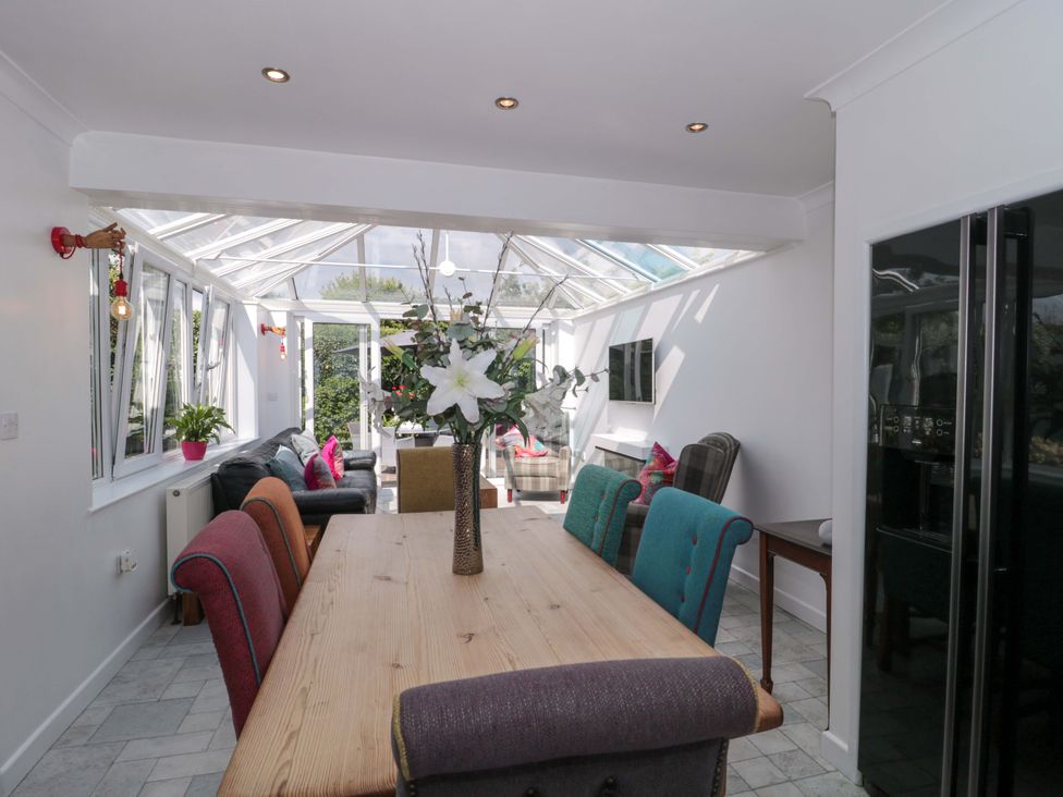 A conservatory with a dining table and seating area at No 8 Burnham-on-Sea