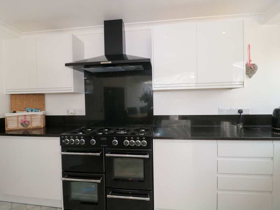 A kitchen with a black oven and white cabinets at No 8 Burnham-on-Sea