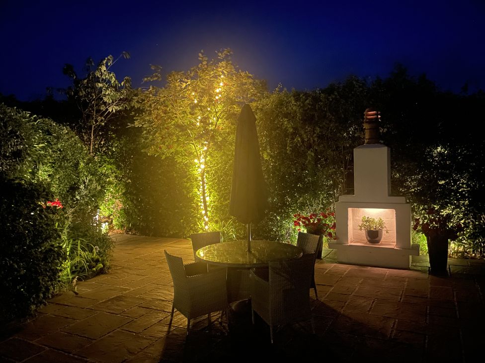 A garden with a table, chairs, and fireplace at No 8 in Burnham-On-Sea