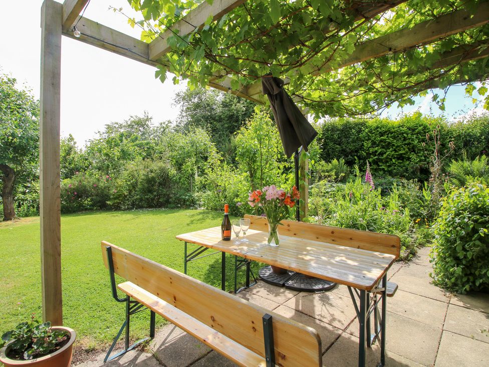A garden with a table and benches under a pergola at Plum Hill in Morda, near Oswestry