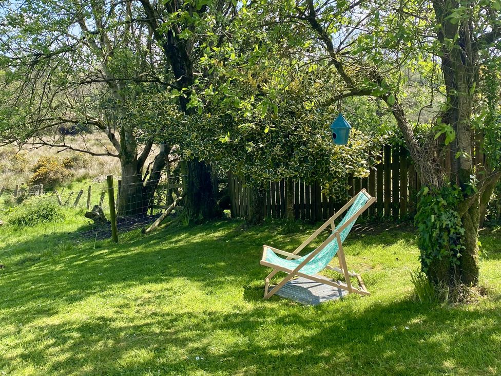 A garden with a deck chair under a tree at Betty's Farm Cottage, Lack near Ederney, County Fermanagh