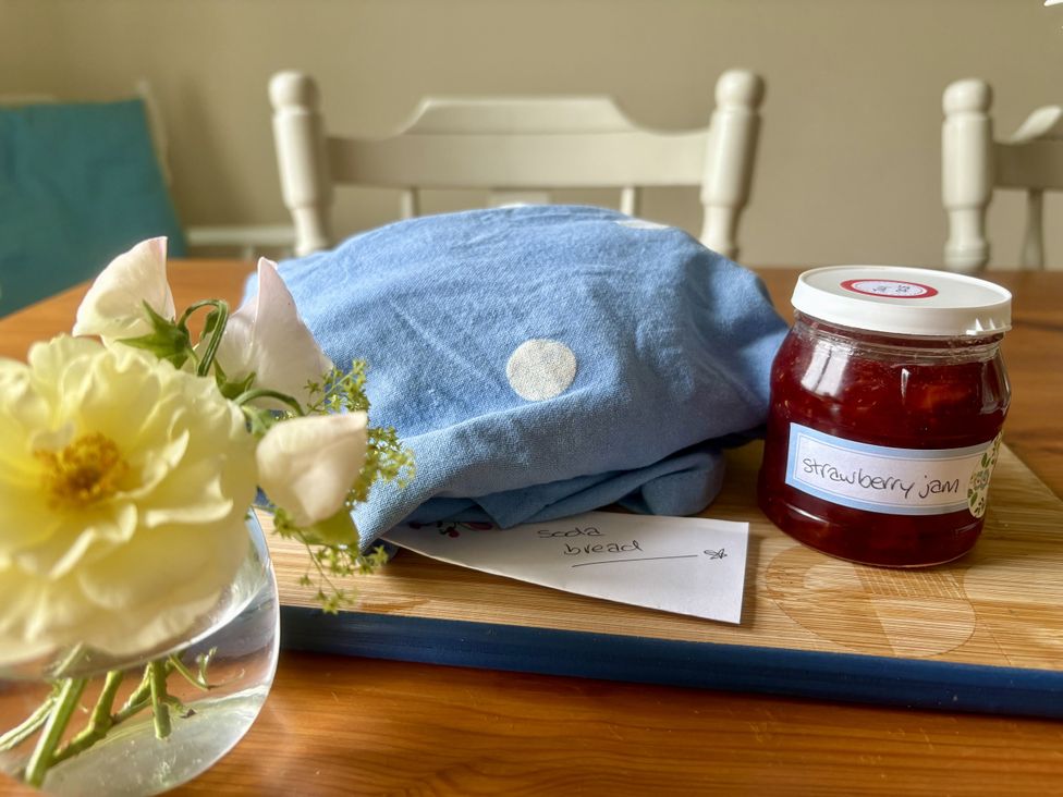 An arrangement with a blue cloth, jar of strawberry jam, flowers, and a note at Betty's Farm Cottage in Lack near Ederney, County Fermanagh