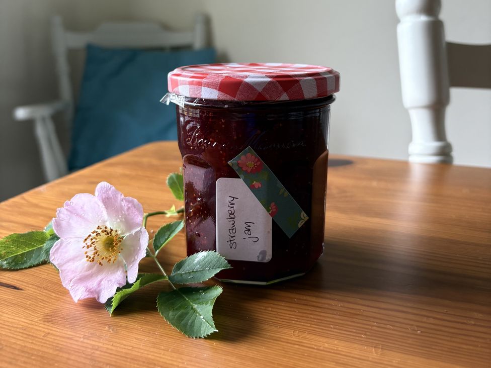 A jar of strawberry jam on a table with a flower and leaf at Betty's Farm Cottage in Lack near Ederney, County Fermanagh