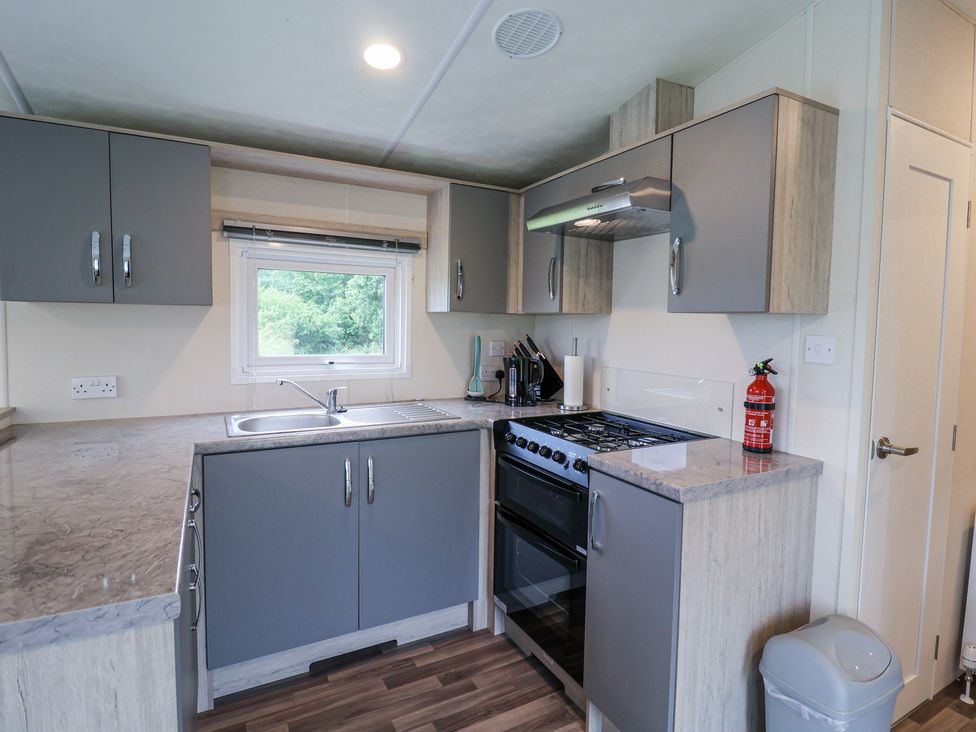 A kitchen with gray cabinets a gas stove a sink a window and a fire extinguisher at The Hoot in Great Finborough near Stowmarket