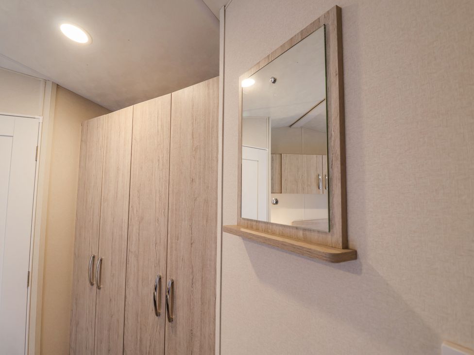 A hallway with wooden wardrobes and a wall-mounted mirror at The Hoot in Great Finborough near Stowmarket