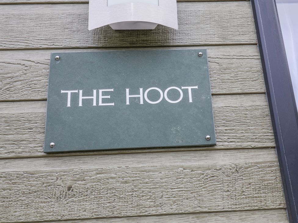A green rectangular sign with the text THE HOOT mounted on wooden planks at The Hoot in Great Finborough near Stowmarket