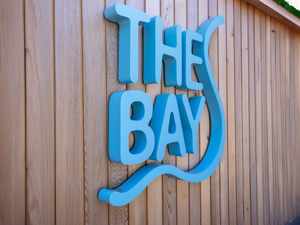 A sign that says THE BAY on a wooden wall at Lodge 65 at Riviera Bay Coastal Retreat Brixham