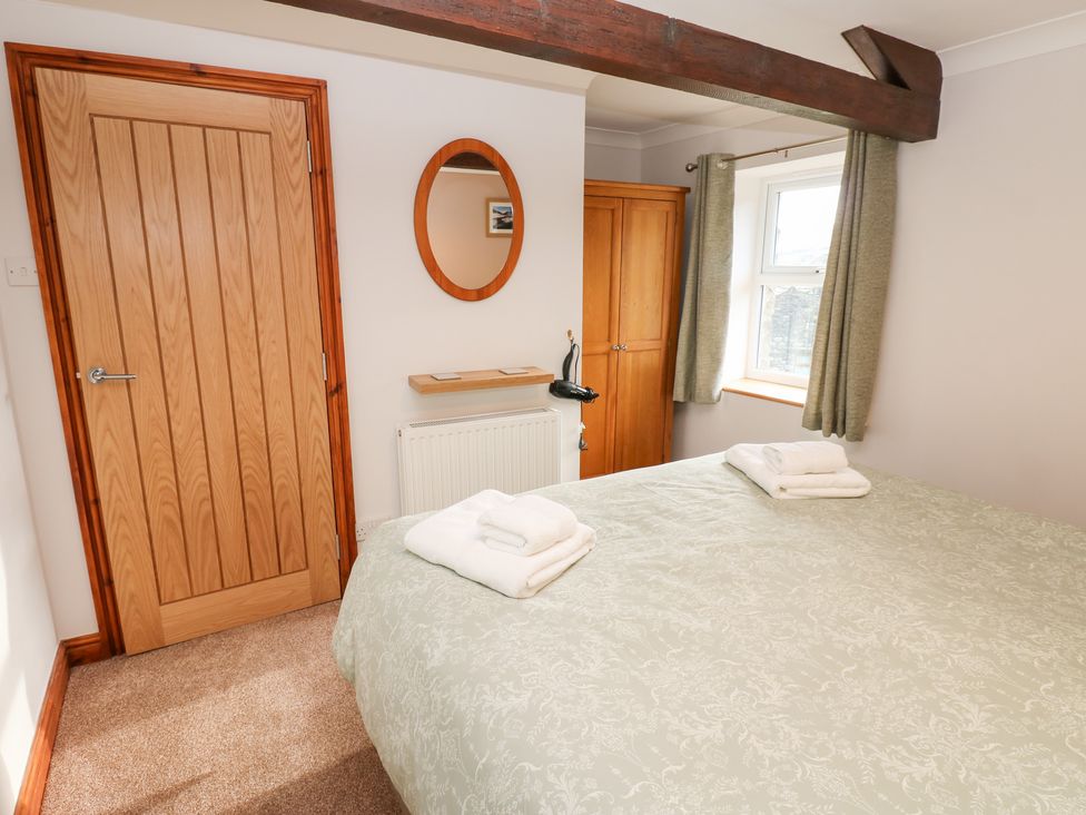 A bedroom with a bed and a mirror at Stoneleigh Cottage in Muker