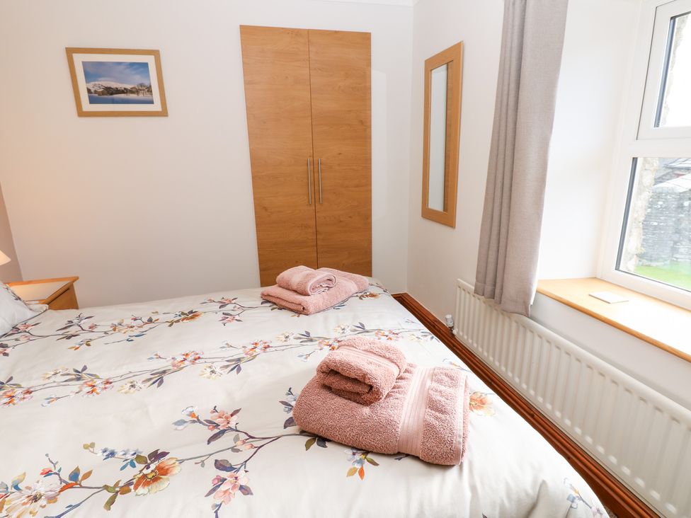 A bedroom with a bed and wardrobe at Stoneleigh Cottage in Muker